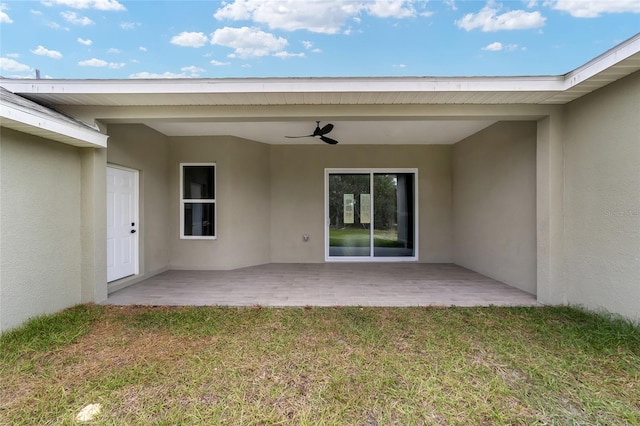 entrance to property featuring a patio area, ceiling fan, and a yard