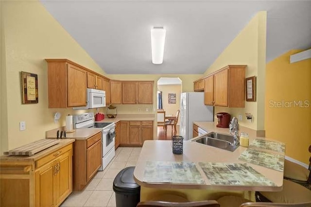 kitchen with lofted ceiling, light tile patterned flooring, white appliances, and sink