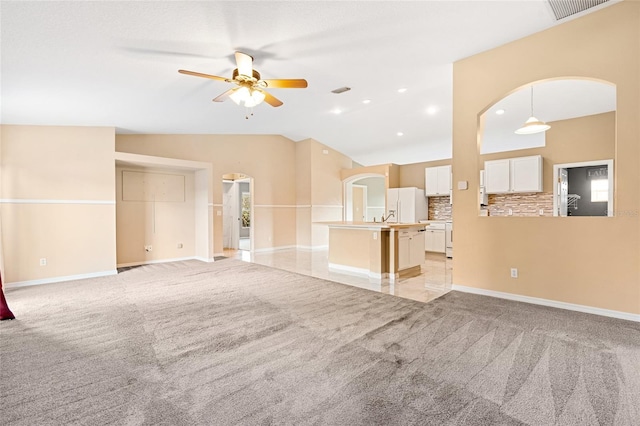 unfurnished living room with light carpet, vaulted ceiling, and ceiling fan