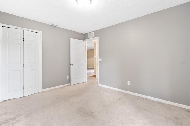 unfurnished bedroom with a textured ceiling, light carpet, and a closet