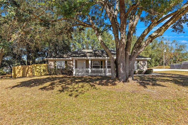 ranch-style home featuring covered porch and a front yard