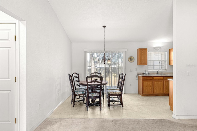 carpeted dining room featuring a textured ceiling, an inviting chandelier, and sink