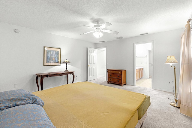 bedroom with a textured ceiling, ceiling fan, ensuite bathroom, and light carpet