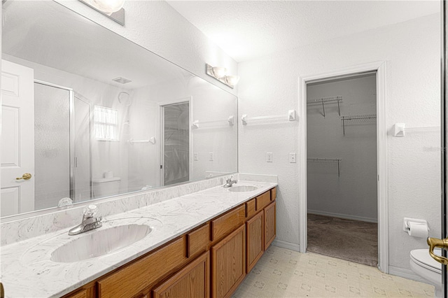 bathroom with vanity, a shower with shower door, and toilet