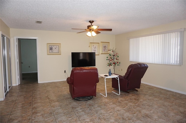 living room with a textured ceiling and ceiling fan