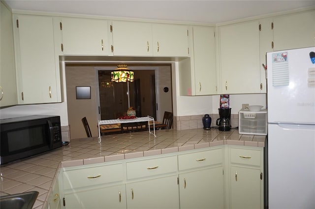 kitchen with white refrigerator and tile counters