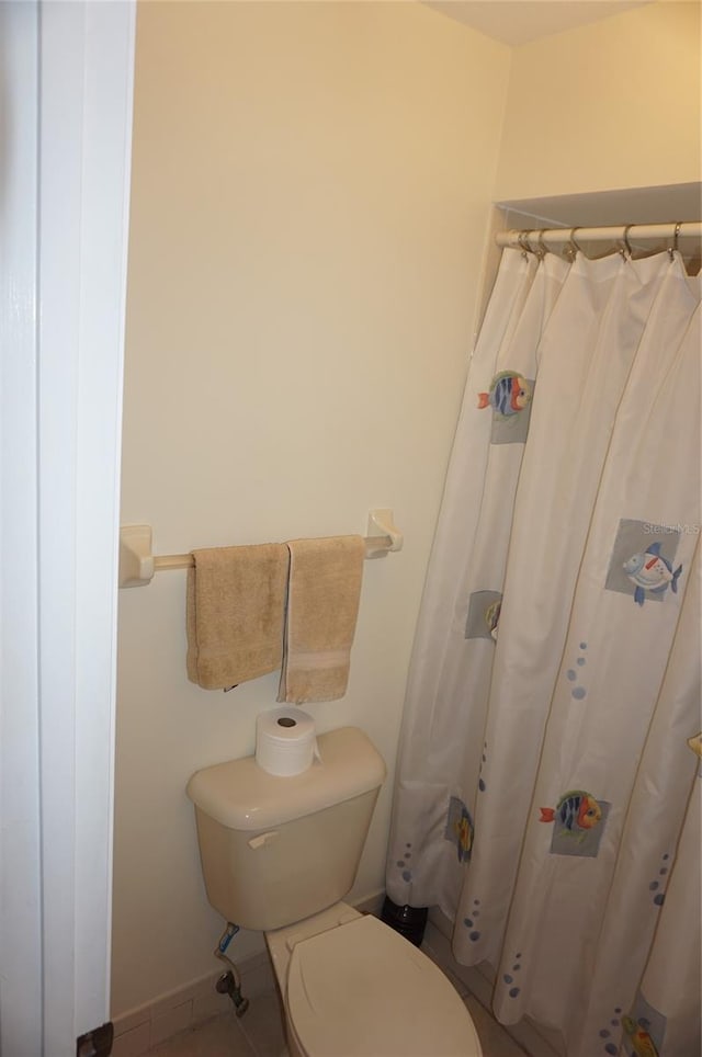 bathroom with a shower with shower curtain and toilet