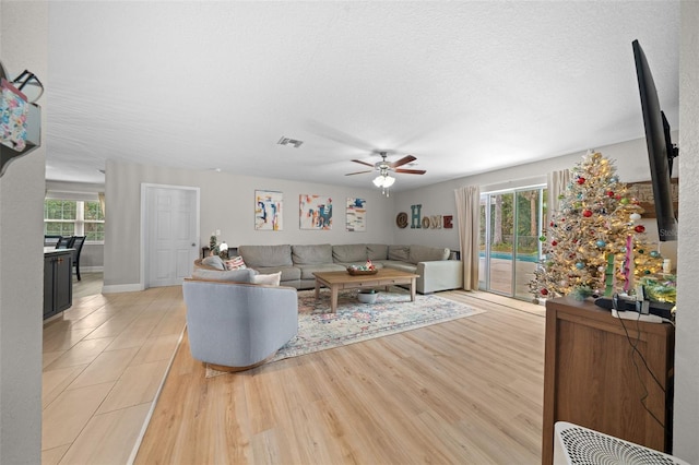 living room with ceiling fan, light hardwood / wood-style floors, and a textured ceiling