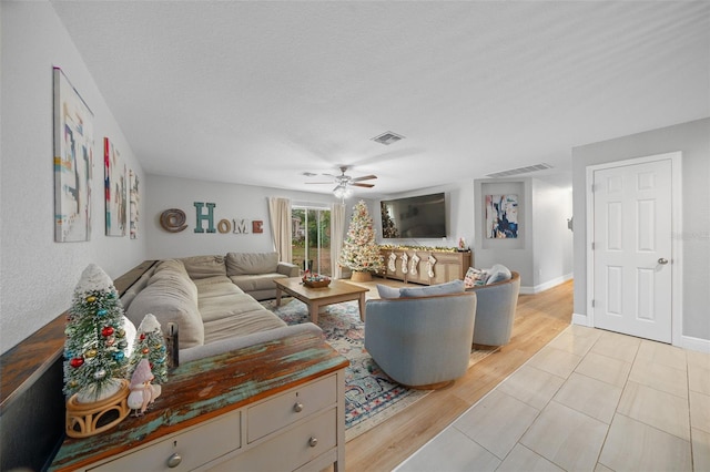 living room with a textured ceiling, light hardwood / wood-style floors, and ceiling fan