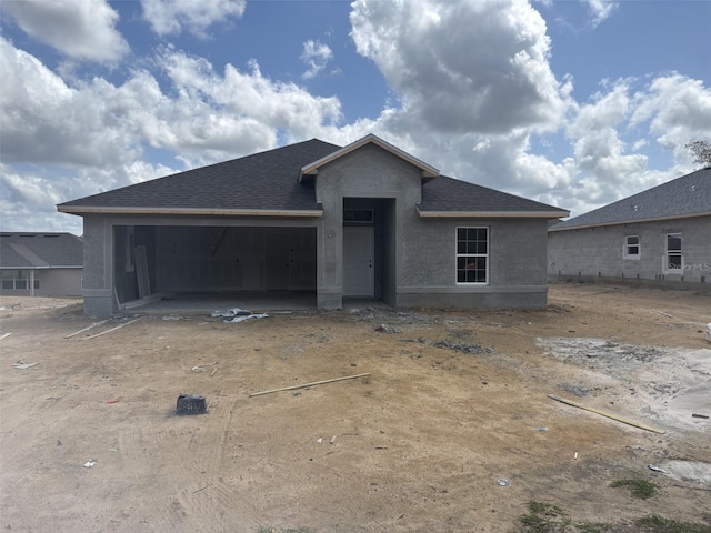 property under construction featuring stucco siding, an attached garage, and roof with shingles