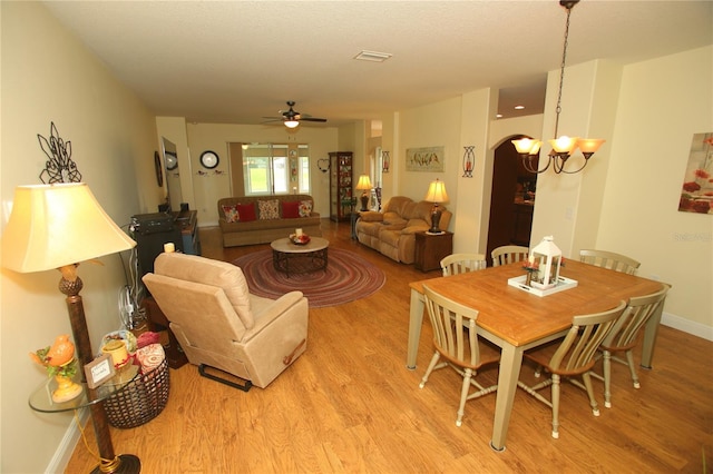 dining area with light hardwood / wood-style floors and ceiling fan with notable chandelier