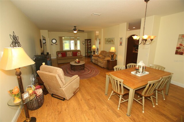 dining area with ceiling fan with notable chandelier and light wood-type flooring