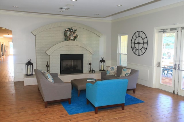 living room featuring hardwood / wood-style flooring, ornamental molding, and plenty of natural light