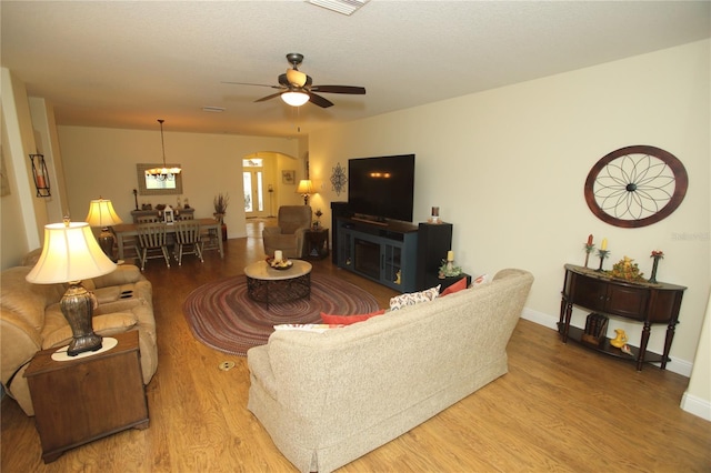 living room with a textured ceiling, light hardwood / wood-style floors, and ceiling fan