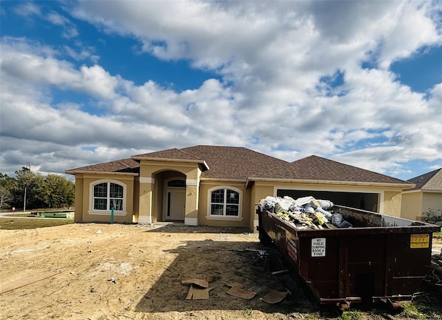 view of front of property featuring roof with shingles and stucco siding