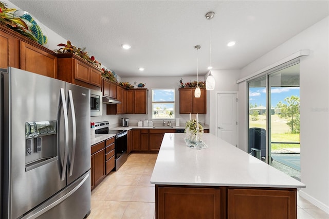 kitchen featuring a textured ceiling, a center island, stainless steel appliances, and decorative light fixtures