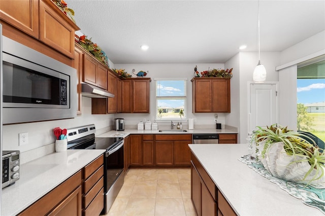 kitchen featuring appliances with stainless steel finishes, a textured ceiling, sink, light tile patterned floors, and pendant lighting