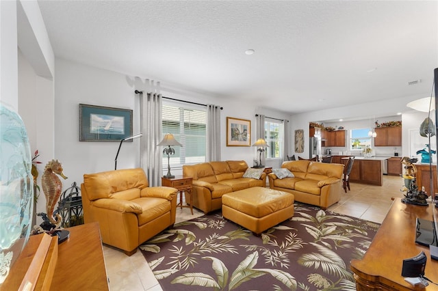 living room featuring light tile patterned floors, a textured ceiling, and a wealth of natural light