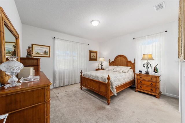 bedroom with light carpet and a textured ceiling