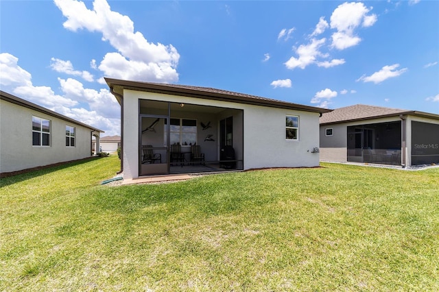 rear view of property featuring a lawn and a sunroom