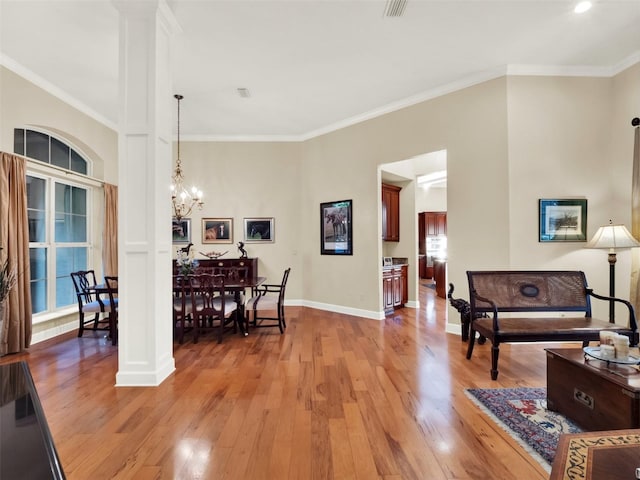 dining room featuring ornamental molding, decorative columns, and light hardwood / wood-style floors