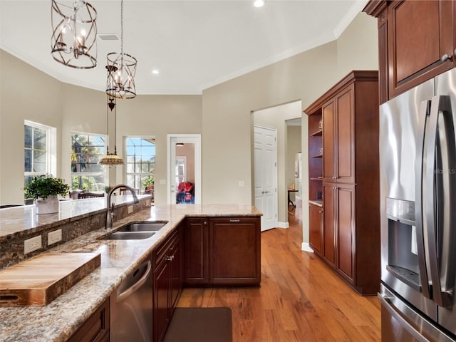 kitchen featuring an inviting chandelier, sink, light wood-type flooring, decorative light fixtures, and stainless steel appliances