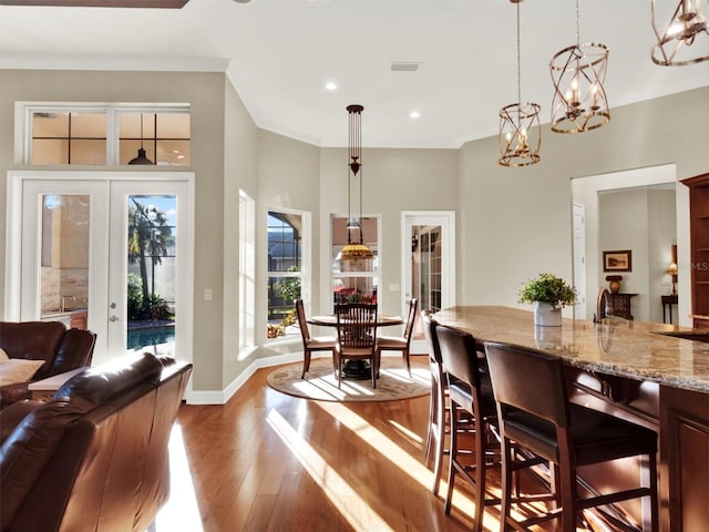 dining room featuring a notable chandelier, wood-type flooring, ornamental molding, and french doors