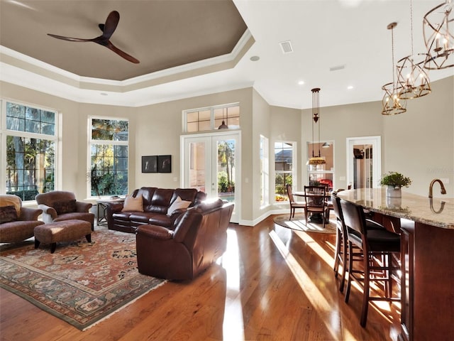 living room with hardwood / wood-style flooring, ceiling fan with notable chandelier, a healthy amount of sunlight, and ornamental molding