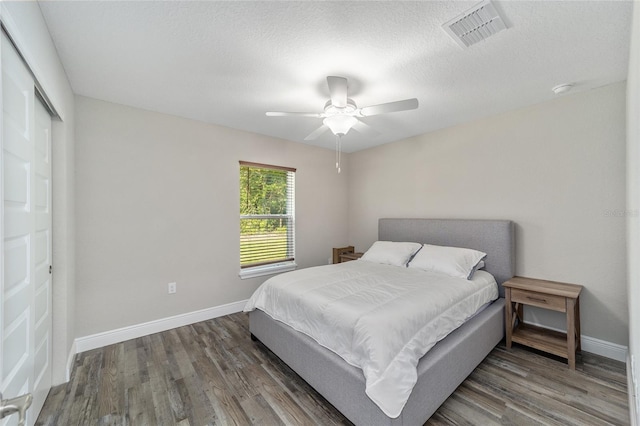 bedroom featuring ceiling fan, dark hardwood / wood-style floors, a textured ceiling, and a closet