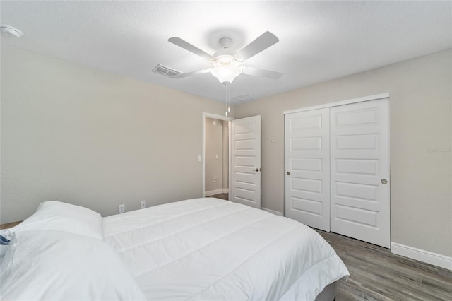 bedroom featuring a textured ceiling, dark hardwood / wood-style flooring, a closet, and ceiling fan