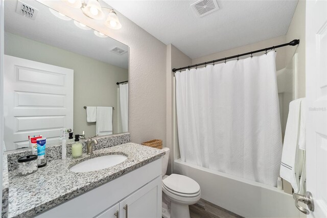 full bathroom featuring hardwood / wood-style floors, vanity, a textured ceiling, and shower / tub combo with curtain