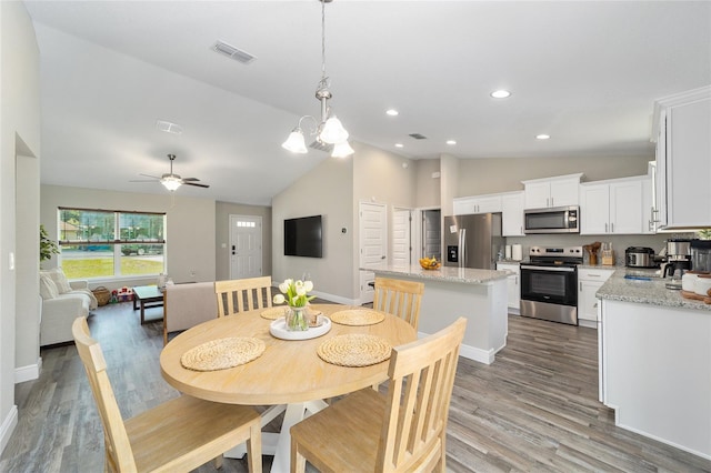 dining room with light hardwood / wood-style flooring, ceiling fan with notable chandelier, and vaulted ceiling