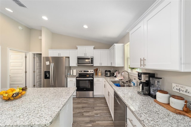 kitchen with stainless steel appliances, vaulted ceiling, sink, dark hardwood / wood-style floors, and white cabinetry