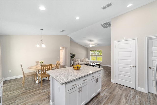 kitchen featuring lofted ceiling, white cabinets, ceiling fan with notable chandelier, hanging light fixtures, and light wood-type flooring