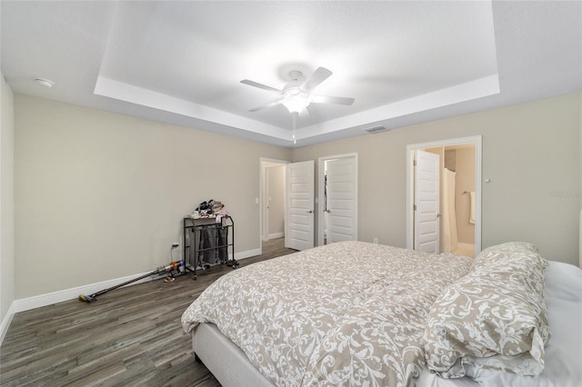 bedroom with a tray ceiling, ceiling fan, and dark hardwood / wood-style floors