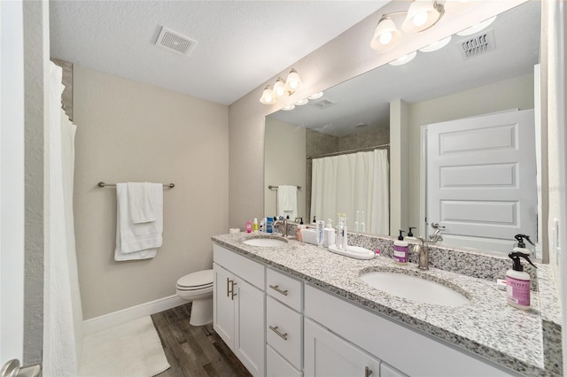 bathroom with a textured ceiling, vanity, hardwood / wood-style flooring, toilet, and curtained shower