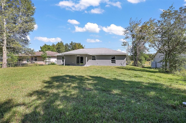 rear view of property with a lawn and stucco siding