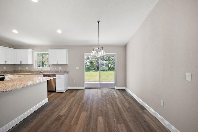 kitchen with baseboards, white cabinets, stainless steel dishwasher, light stone countertops, and decorative light fixtures