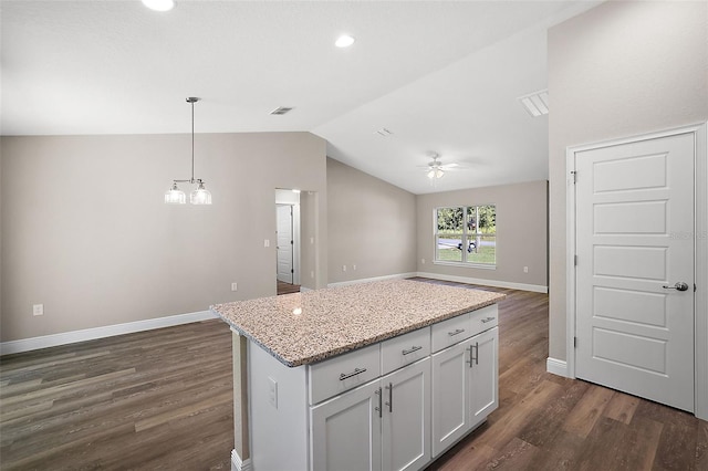 kitchen with white cabinets, a kitchen island, light stone counters, open floor plan, and decorative light fixtures