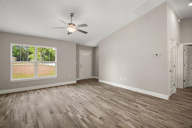 unfurnished living room with wood finished floors, ceiling fan, baseboards, visible vents, and lofted ceiling