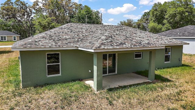 rear view of property with a patio, a yard, and stucco siding