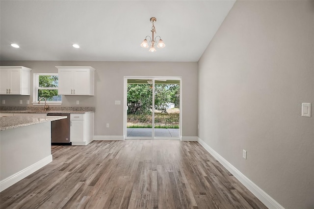 kitchen with baseboards, light stone countertops, stainless steel dishwasher, light wood-style floors, and white cabinetry