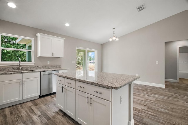 kitchen featuring wood finished floors, stainless steel dishwasher, plenty of natural light, a sink, and visible vents