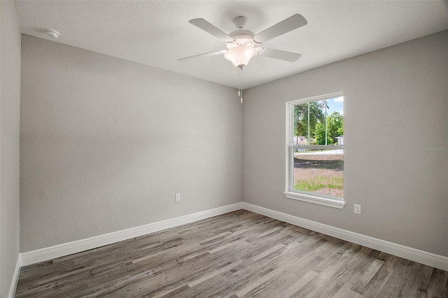 spare room with baseboards, wood finished floors, and a ceiling fan
