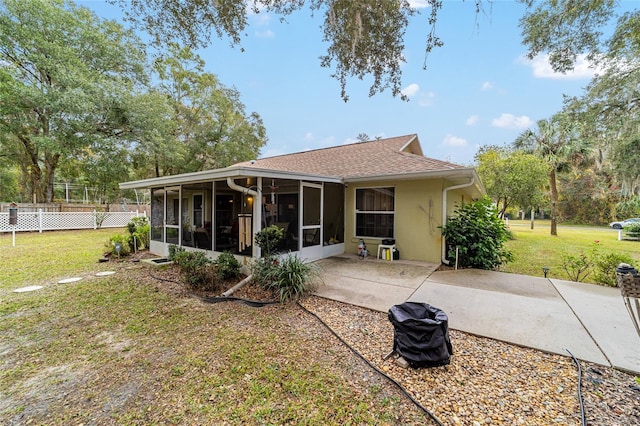 back of property featuring a sunroom, a patio, and a lawn