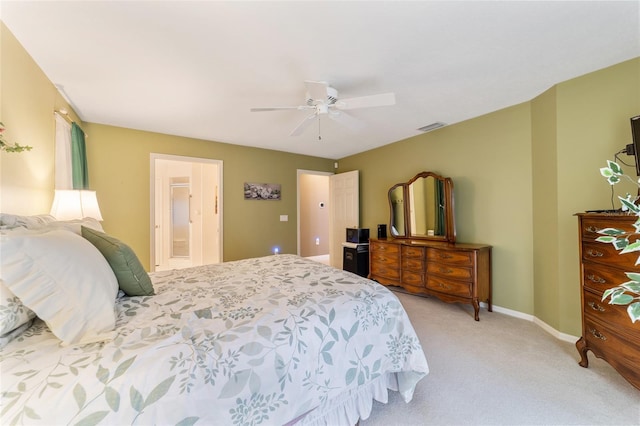 bedroom with light colored carpet, ceiling fan, and ensuite bathroom