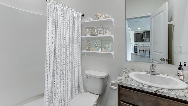 bathroom with curtained shower, vanity, and toilet