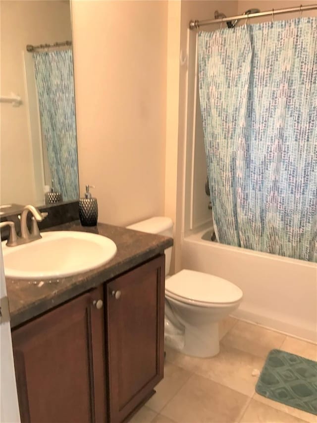 full bathroom with tile patterned floors, vanity, toilet, and shower / bath combo with shower curtain