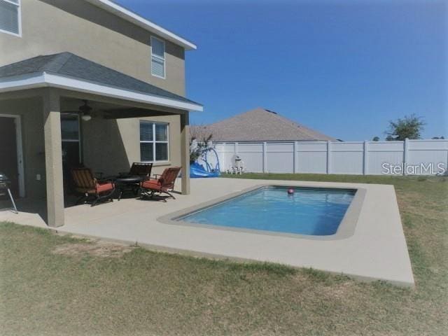 view of swimming pool with ceiling fan, a yard, and a patio