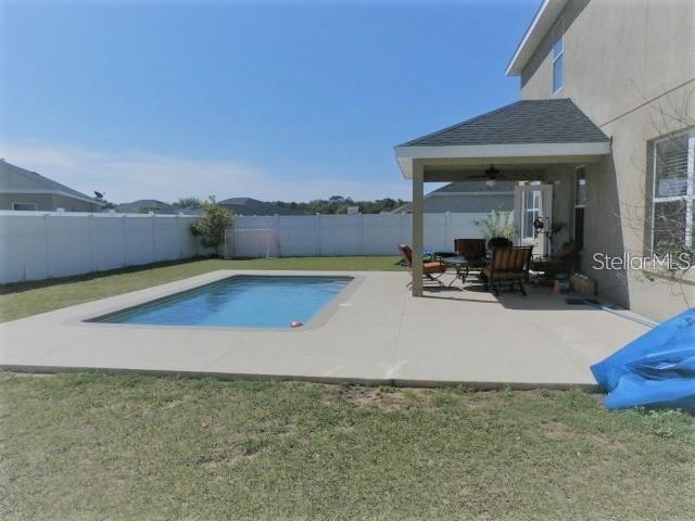 view of swimming pool with ceiling fan, a patio area, and a yard